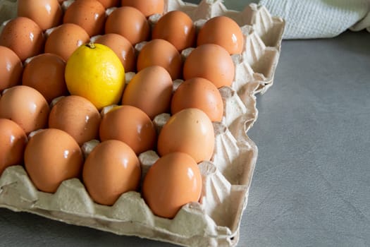 Chicken eggs lie in a tray on a kitchen surface with a yellow lemon. Buying products and goods in the store