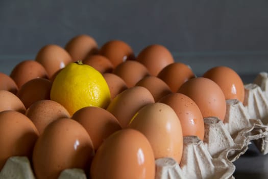 Chicken eggs lie in a tray on a kitchen surface with a yellow lemon. Buying products and goods in the store