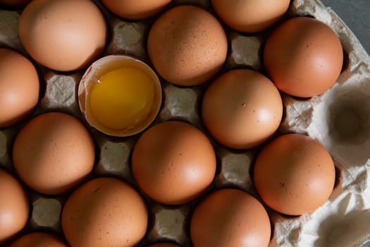 Chicken eggs lie in a tray on the kitchen surface with a broken yellow yolk. Buying products and goods in the store