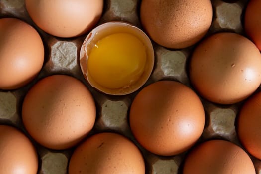 Chicken eggs lie in a tray on the kitchen surface with a broken yellow yolk. Buying products and goods in the store