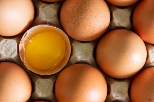 Chicken eggs lie in a tray on the kitchen surface with a broken yellow yolk. Buying products and goods in the store