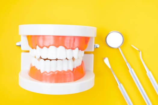 Dentures model and instrument dental on yellow background.