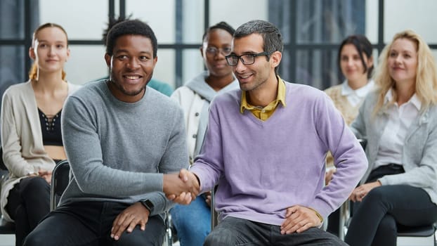 Young people enjoying spending time together on special group therapy. Handsome joyful guy talking jokes and making fun.