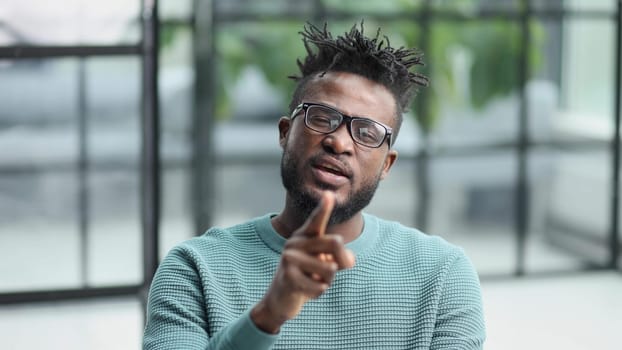 Portrait of a serious african american man, shaking his finger, warning and preventing you from something bad, looking at the camera with a worried expression.
