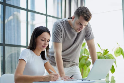 male ceo executive manager mentor giving consultation on financial operations to female colleague intern using laptop sitting in modern office