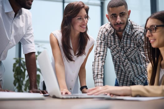Diverse group of coworkers listening to a presentation during a staff meeting around a table in an office