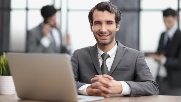Portrait of attractive smiling man sitting in office and looking at camera.