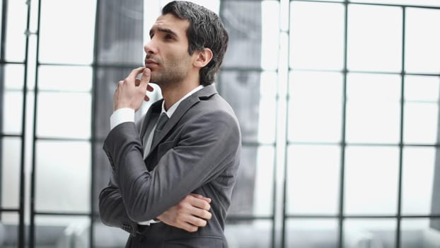Young business man in profile view with hand on chin in office