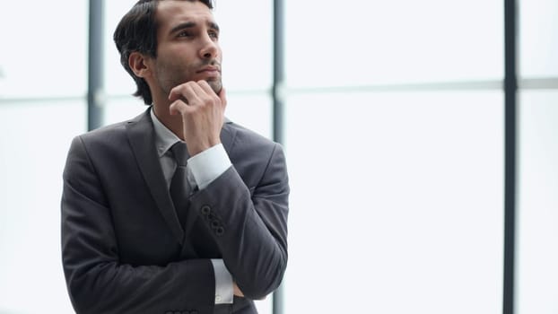 Young business man in profile view with hand on chin in office