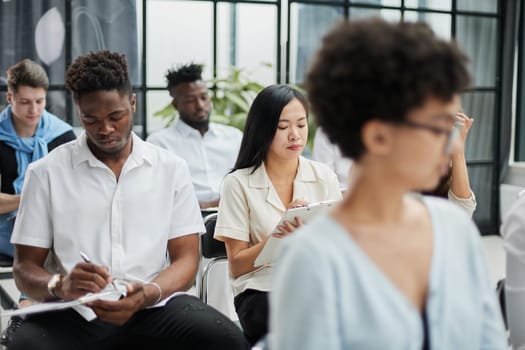 Business team sits in a conference room and writes a lecture in a notebook