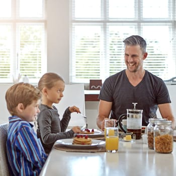 Hes a proud father. a man enjoying breakfast with his two children