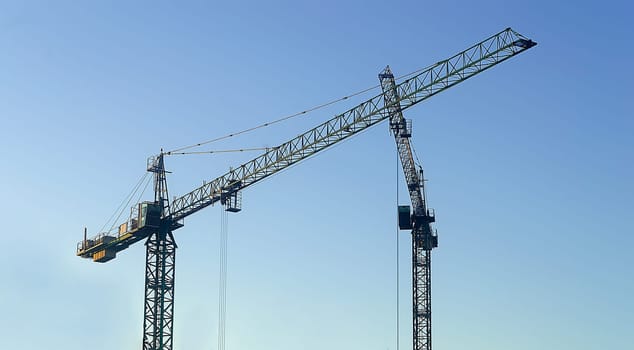 Two construction crane on blue sky.