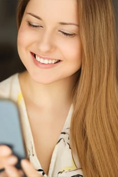 Beautiful happy woman using her mobile phone for online shopping and smiling, face portrait with natural make-up and casual lifestyle mood at home.