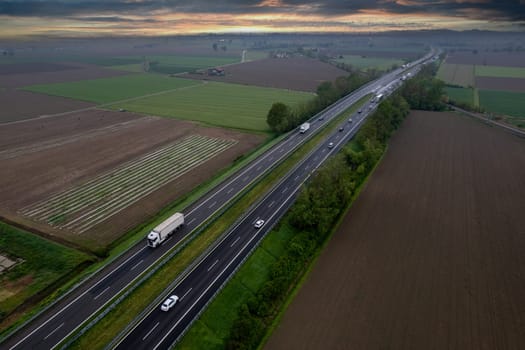 Cargo trucks and cars in the motorway a1 autostrada del sole aerial point of view in between padain plain rural fields