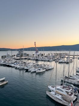 Crane stands on a pier among moored yachts against the backdrop of mountains at sunset. High quality photo