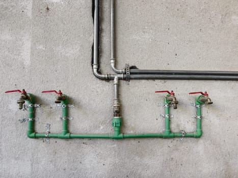 Distribution of water taps on a concrete wall next to pipes. High quality photo