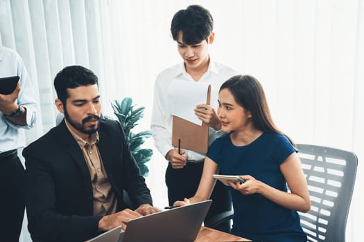 Professional Asian employee work together as team in corporate office, discussing business plans and data to achieve success on desk with laptop. Modern office worker teamwork concept. Concord