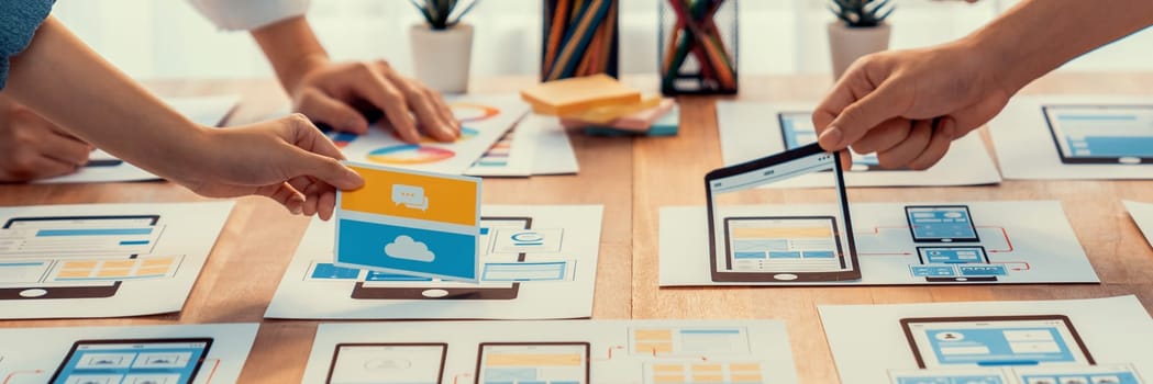 Panorama shot of front-end developer team brainstorming UI and UX designs for mobile app on paper wireframe interface. User interface development team planning for user-friendly UI design. Scrutinize