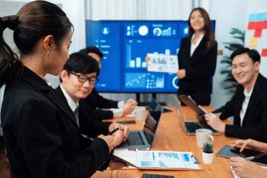 Confidence and young asian businesswoman give presentation on financial business strategy in dashboard report display on screen to colleagues in conference room meeting as harmony in workplace concept