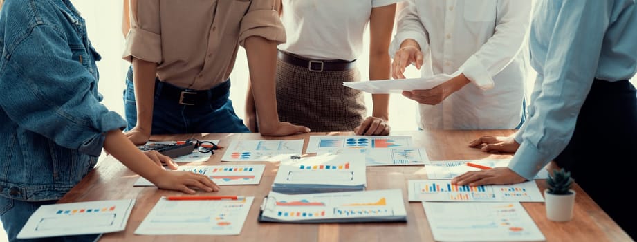 Analyst team utilizing BI Fintech to analyze and pointing at financial dashboard paper office. Businesspeople examining report paper on table for business insight. Panorama shot. Scrutinize