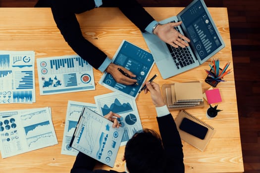 Top view analyst team discussing financial data on digital dashboard, analyzing chart and graph papers by data science software on wooden table background. Business intelligence and Fintech. Fervent