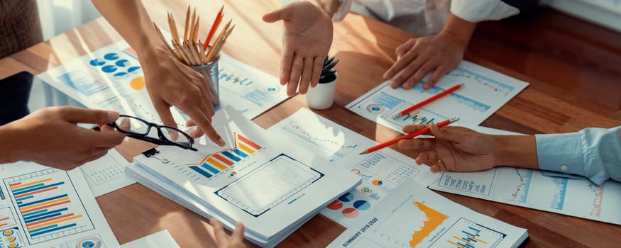 Analyst team utilizing BI Fintech to analyze and pointing at financial dashboard paper office. Businesspeople examining report paper on table for business insight. Panorama shot. Scrutinize