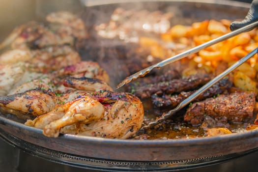 Fast food cooking process. A man flips food in a large pan for a town feast with tongs. High quality photo.