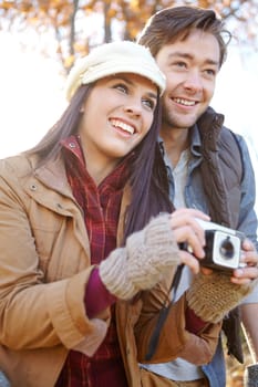 Savoring the beauty of nature. A beautiful young woman standing alongside her boyfriend outdoors in the woods while holding her camera