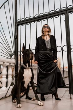 A woman walks with her Great Dane in an urban setting, enjoying the outdoors and the company of her dog