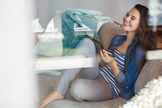 Shopping online is so much more convenient. an attractive young woman using her tablet to shop online while relaxing on the sofa at home