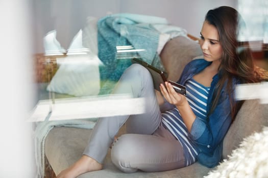 Shes browsing some of her favourite shops. an attractive young woman using her tablet to shop online while relaxing on the sofa at home