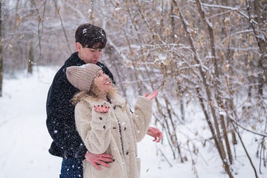 A young couple walks in the park in winter. Guy and girl hugging outdoors