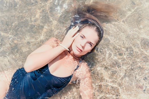 Woman travel sea. Young Happy woman in a long red dress posing on a beach near the sea on background of volcanic rocks, like in Iceland, sharing travel adventure journey