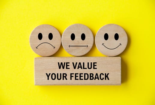 We value your feedback text on wooden block with happy, sad and neutral emoticon faces on wooden circle. Customer feedback, satisfaction and evaluation and concept.