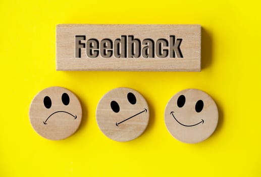 Feedback text on wooden block with happy, sad and neutral emoticon faces on wooden circle with white background cover. Customer feedback, satisfaction and evaluation and concept