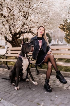 A woman walks with her Great Dane in an urban setting, enjoying the outdoors and the company of her dog