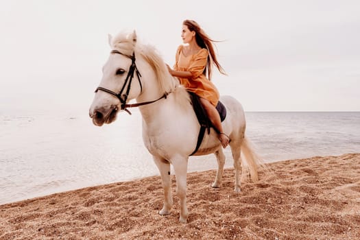 A woman in a dress stands next to a white horse on a beach, with the blue sky and sea in the background