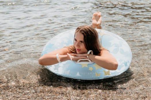 Woman summer sea. Happy woman swimming with inflatable donut on the beach in summer sunny day, surrounded by volcanic mountains. Summer vacation concept