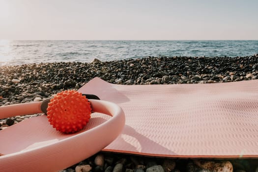 Young woman with long hair in white swimsuit and boho style braclets practicing outdoors on yoga mat by the sea on a sunset. Women's yoga fitness routine. Healthy lifestyle, harmony and meditation