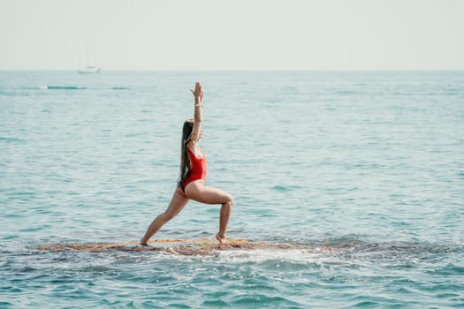 Woman sea yoga. Back view of free calm happy satisfied woman with long hair standing on top rock with yoga position against of sky by the sea. Healthy lifestyle outdoors in nature, fitness concept.