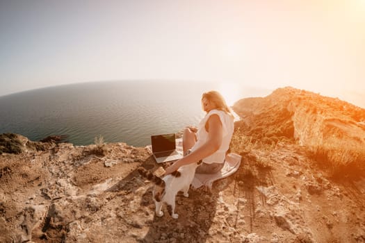 Woman sea laptop. Business woman in yellow hat working on laptop by sea. Close up on hands of pretty lady typing on computer outdoors summer day. Freelance, digital nomad, travel and holidays concept.