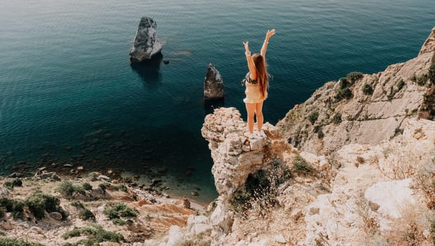 Woman travel sea. Happy tourist taking picture outdoors for memories. Woman traveler looks at the edge of the cliff on the sea bay of mountains, sharing travel adventure journey.