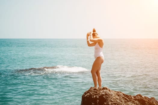 Woman sea yoga. Back view of free calm happy satisfied woman with long hair standing on top rock with yoga position against of sky by the sea. Healthy lifestyle outdoors in nature, fitness concept