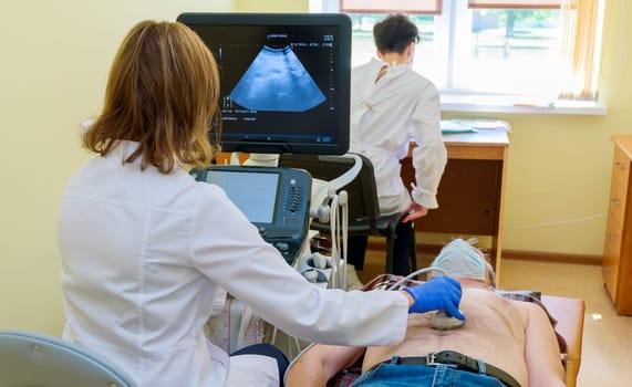A patient in the clinic examines his abdominal cavity while lying on the bed.