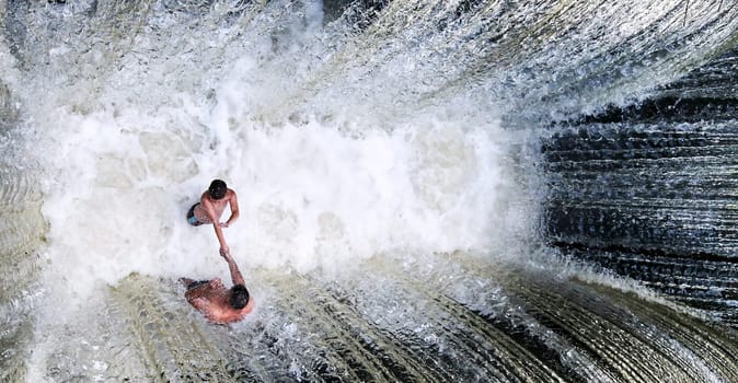 Two people swim in the pool of the waterfall. Water intake on the lake.