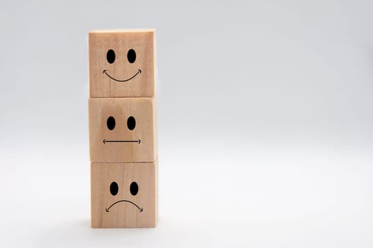 Happy, sad and neutral emoticon faces on stacking wooden cubes with white background cover. Customer satisfaction and evaluation concept