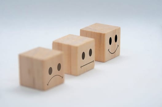 Sad, neutral and happy emoticon faces on wooden cubes with white background cover. Customer satisfaction and evaluation concept