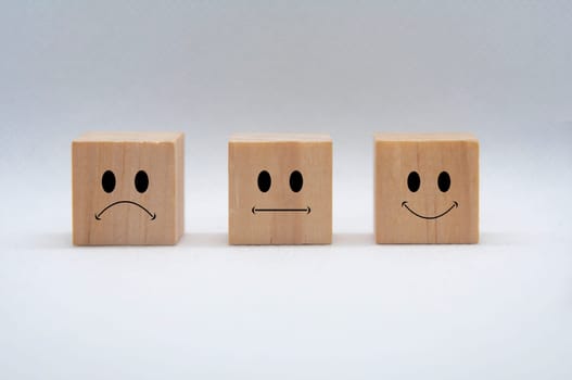 Sad, neutral and happy emoticon faces on wooden cubes with white background cover. Customer feedback, satisfaction and evaluation concept.