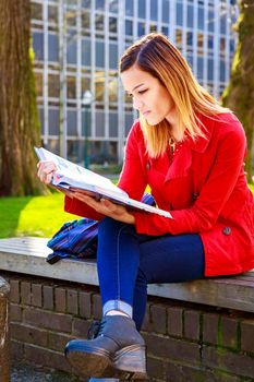 A young female college student study books outside of library.