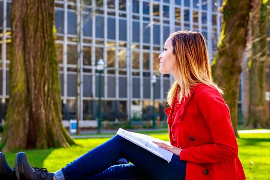 A young female college student study books outside of library.